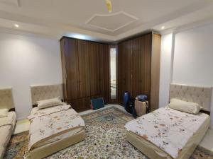 a bedroom with two beds and a large rug at Fatih Hostel for Males in ‘Urwah