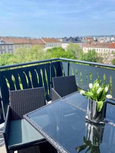 una mesa de cristal con sillas y un jarrón con flores en el balcón en My Perfect Penthouse, en Viena