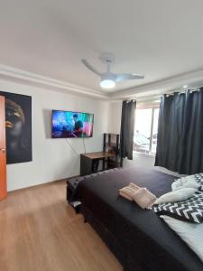 a bedroom with a black bed and a tv on the wall at Apt próximo ao Consulado in Porto Alegre