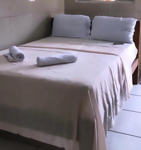 a bed with white sheets and pillows on it at Hotel Planalto in Conceição do Araguaia