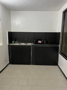 Una cocina con gabinetes negros y un fregadero. en Le cocon by sdm, en Dakar 4 fotos más