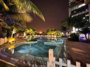 uma piscina à noite com palmeiras e edifícios em Luna's House - Vinhomes D'Capitale - 2Br Apt em Hanói