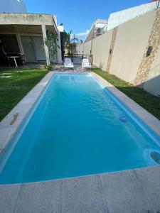 a blue swimming pool in front of a house at Casa en alquiler temporario Formosa in Formosa