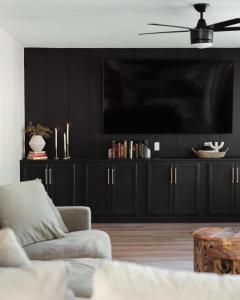 een woonkamer met een grote televisie op een zwarte muur bij *NEW* La Maison Meza in Avondale