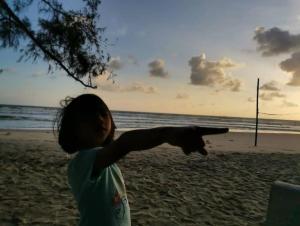 a young girl is pointing at the beach at Chalet Barokah Resort, Bachok in Bachok