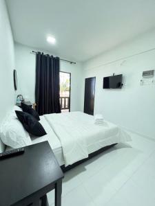 萬捷的住宿－Chalet Barokah Resort, Bachok，卧室配有一张白色大床和电视。