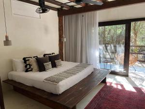 a bedroom with a large bed and a balcony at Amor Rooms in Tulum