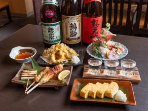 una mesa cubierta con platos de comida y botellas de vino en Hotel Monzennoyu, en Joetsu