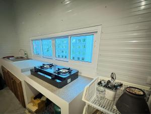 una cucina con piano cottura e bancone con finestra di บ้านพูลวิลล่าอุดรธานี by บ้านแสนรัก a Udon Thani