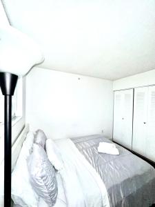 a white bedroom with a bed and a lamp at Private bedroom 1 block from Downtown Miami in Miami