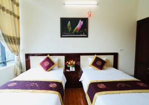 duas camas num quarto de hotel com paredes brancas em Agri Hotel Điện Biên Phủ - by Bay Luxury em Dien Bien Phu