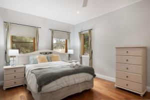 a bedroom with a large bed and two windows at Strong Farmers Cottage Willunga in Willunga