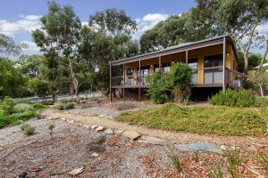 a house with a balcony in the middle of a yard at Strong Farmers Cottage Willunga in Willunga