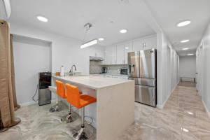 a kitchen with white cabinets and an island with orange chairs at Upper East Side Luxury 3BR 2B in New York