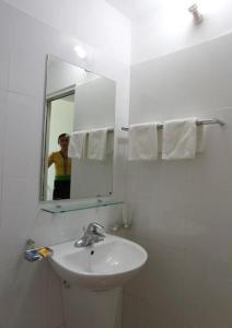 una persona que toma una foto de un baño con lavabo en Agri Hotel Điện Biên Phủ - by Bay Luxury, en Diện Biên Phủ