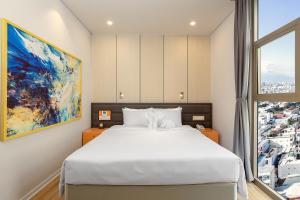 um quarto com uma cama branca e uma grande janela em GRAND CITIVIEW DANANG em Da Nang