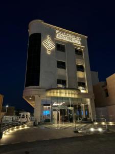 a large building with a sign on it at night at Hotel ALdoliaa in Unayzah