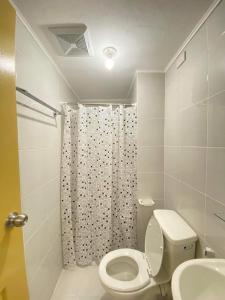 a bathroom with a toilet and a shower curtain at One Spatial Condo in Iloilo City