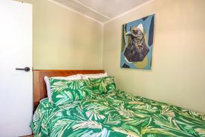 a bedroom with a bed and a picture of a bird at Little Ocean Hideaway in Oneroa