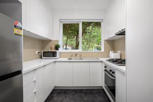 a white kitchen with a sink and a window at Complete Host Cromwell Rd Apartments in Melbourne