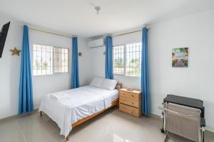Schlafzimmer mit blauen Vorhängen, einem Bett und einem Schreibtisch in der Unterkunft Casa cerca SDQ & Bus Caribe tours in Santo Domingo