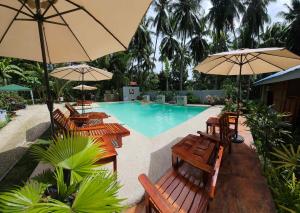 a swimming pool with wooden chairs and umbrellas at House Rental Banaba Tree in Samboan