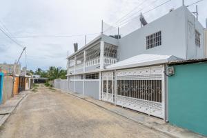 ein weißes Gebäude mit einem Tor auf einer Straße in der Unterkunft Casa cerca SDQ & Bus Caribe tours in Santo Domingo