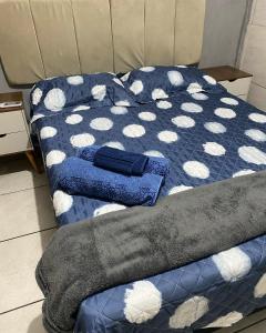 uma cama com um edredão azul e branco em Casa Rute - Conforto em primeiro lugar! em Fortaleza