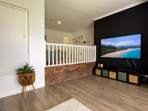a living room with a large flat screen tv on a wall at Shailer Park Serenity in Tanah Merah
