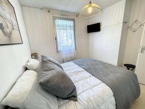 um quarto com uma cama com almofadas e uma janela em Appartement Jullouville, 2 pièces, 4 personnes - FR-1-361-14 em Jullouville-les-Pins