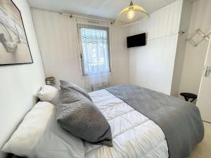 ein Schlafzimmer mit einem Bett mit Kissen und einem Fenster in der Unterkunft Appartement à 50m plage avec terrasse et jardin - FR-1-361-14 in Jullouville-les-Pins