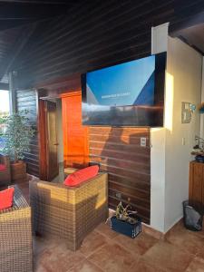 a living room with two wicker chairs and a large screen television at Rooftop Paradise in San Francisco de Macorís
