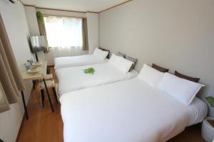 東京にあるルアナ錦ビルの白いシーツと窓が備わる客室のベッド2台