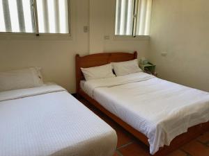 Habitación pequeña con 2 camas y 2 ventanas en Housha Homestay, en Jinning