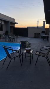 três cadeiras e uma mesa ao lado de uma piscina em Casa com piscina e churrasqueira em Bonito