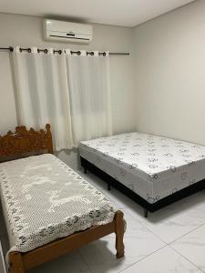 Duas camas num quarto com uma janela em Casa com piscina e churrasqueira em Bonito