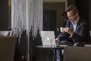 a man sitting at a table with a laptop at The Queens Gate Hotel in London