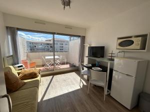 a living room with a couch and a kitchen with a window at Studio cabine à Sète avec terrasse et climatisation - FR-1-338-106 in Sète