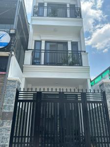 a white house with a black fence in front of it at Kōzē Mini Apartment in Da Lat