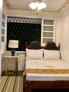 a bedroom with a bed and a table with a lamp at Courtyard Hotel in Manila