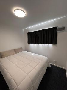 sypialnia z białym łóżkiem i oknem w obiekcie Terapa Motor inn w mieście Hamilton