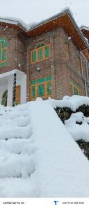 um pátio coberto de neve em frente a um edifício em The Himalayan Inn homestay em Gulmarg