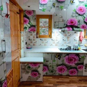 uma cozinha com flores cor-de-rosa na parede em The Himalayan Inn homestay em Gulmarg