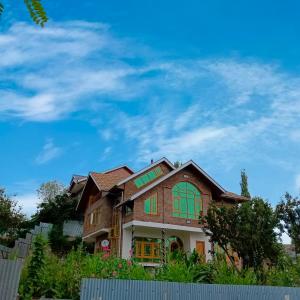 ein Haus mit grünen Fenstern und blauem Himmel in der Unterkunft The Himalayan Inn homestay in Gulmarg