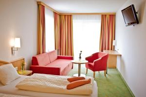 ein Hotelzimmer mit einem Bett, einem Sofa und einem Stuhl in der Unterkunft Der Thomashof in Sankt Jakob im Rosental