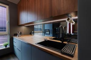 a kitchen with a sink and wooden cabinets at Oceanview Apartment baltyk Gdynia in Gdynia