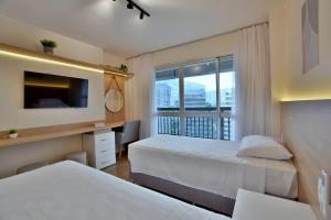 a hotel room with two beds and a window at BSB Stay Flats Particulares - SHN in Brasilia