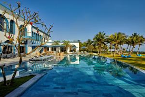 a pool at a resort with palm trees and a building at Wyndham Hoi An Royal Beachfront Resort & Villas in Hoi An