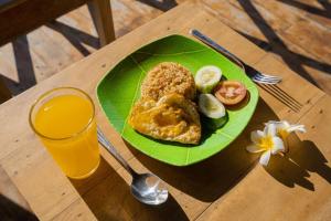 um prato verde com ovos e legumes e um copo de sumo de laranja em Govinda villa em Nusa Penida