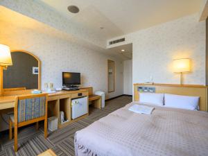 a hotel room with a bed and a desk and a television at Hotel Green Park Suzuka in Suzuka